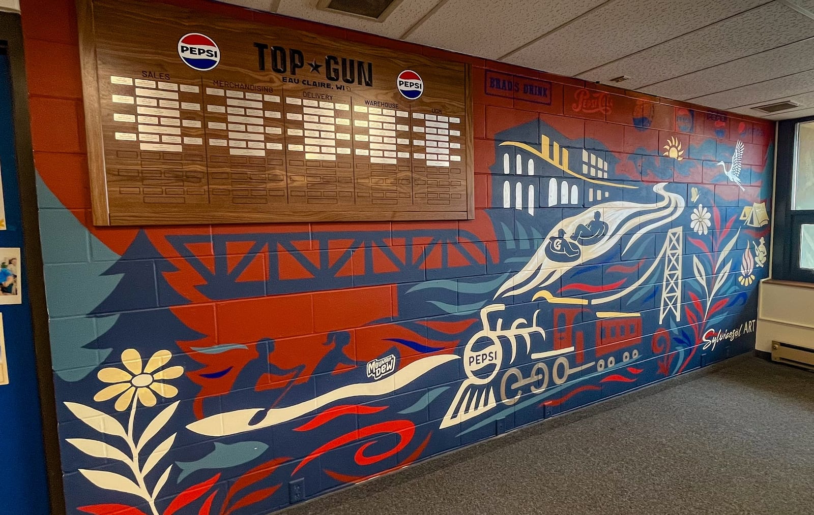 PepsiCo mural in Eau Claire with a Top Gun recognition board, a vintage train, and regional landmarks.